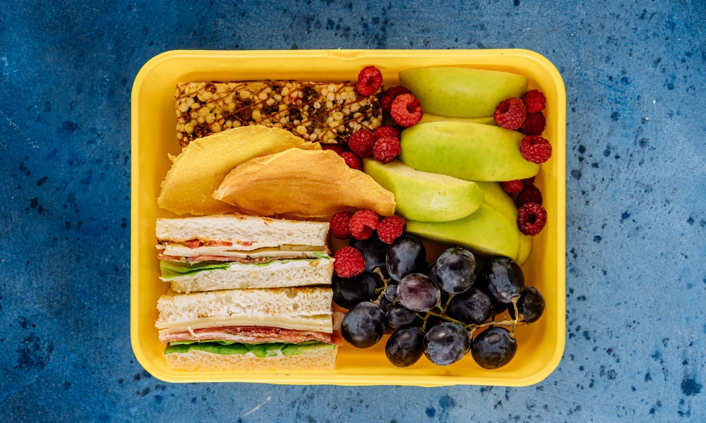 Lunch with a sandwich, granola bar, and assorted fruit