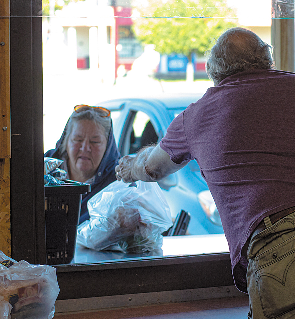 Catholic Charities Food Pantry volunteer hands a woman 