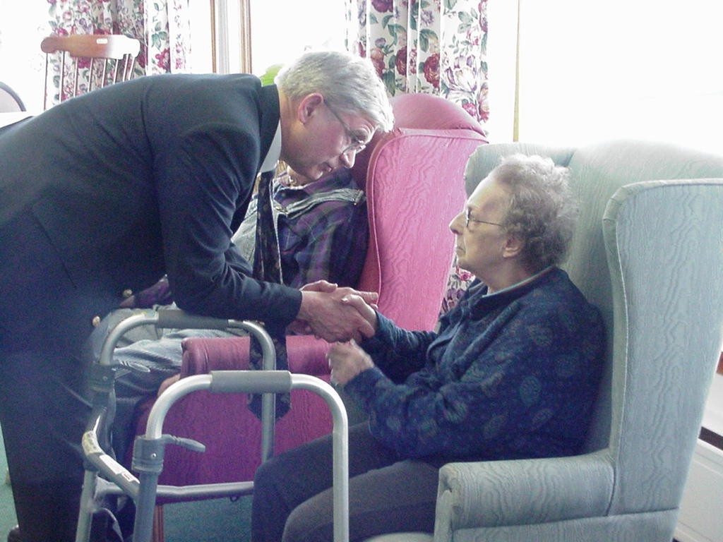 Deacon Fred Cornwell greets an elderly woman. 