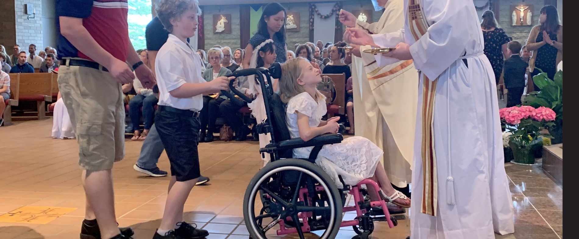 Little girl in a wheelchair receives her First Holy Com