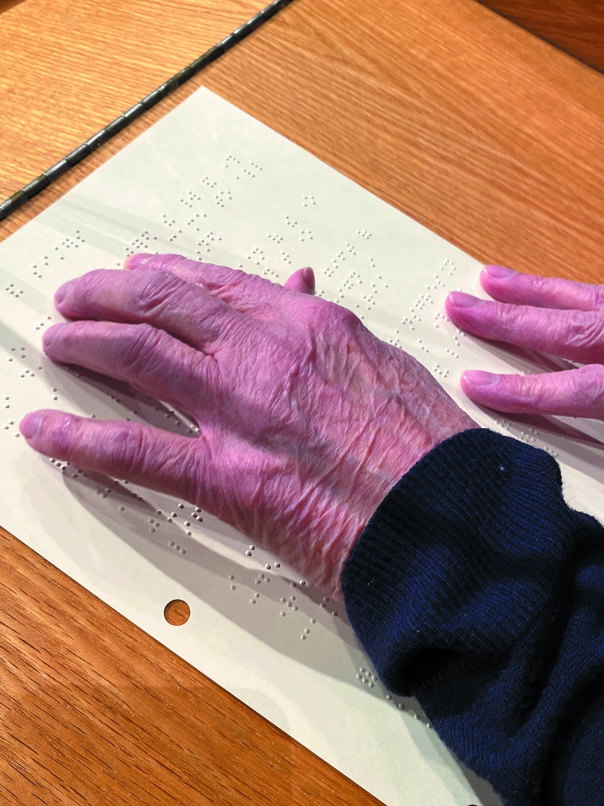 Mary Clarke's hand goes over braille letters