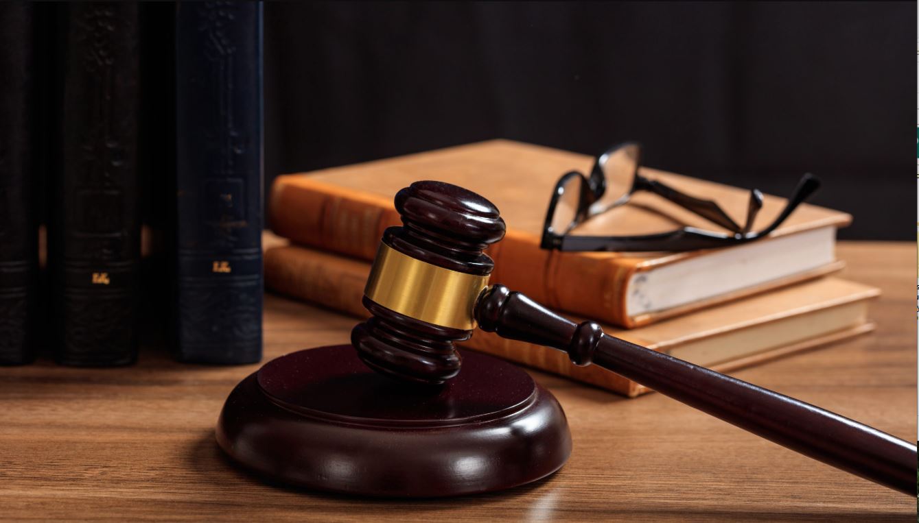 gavel on stand, stacked books with glasses sitting on top