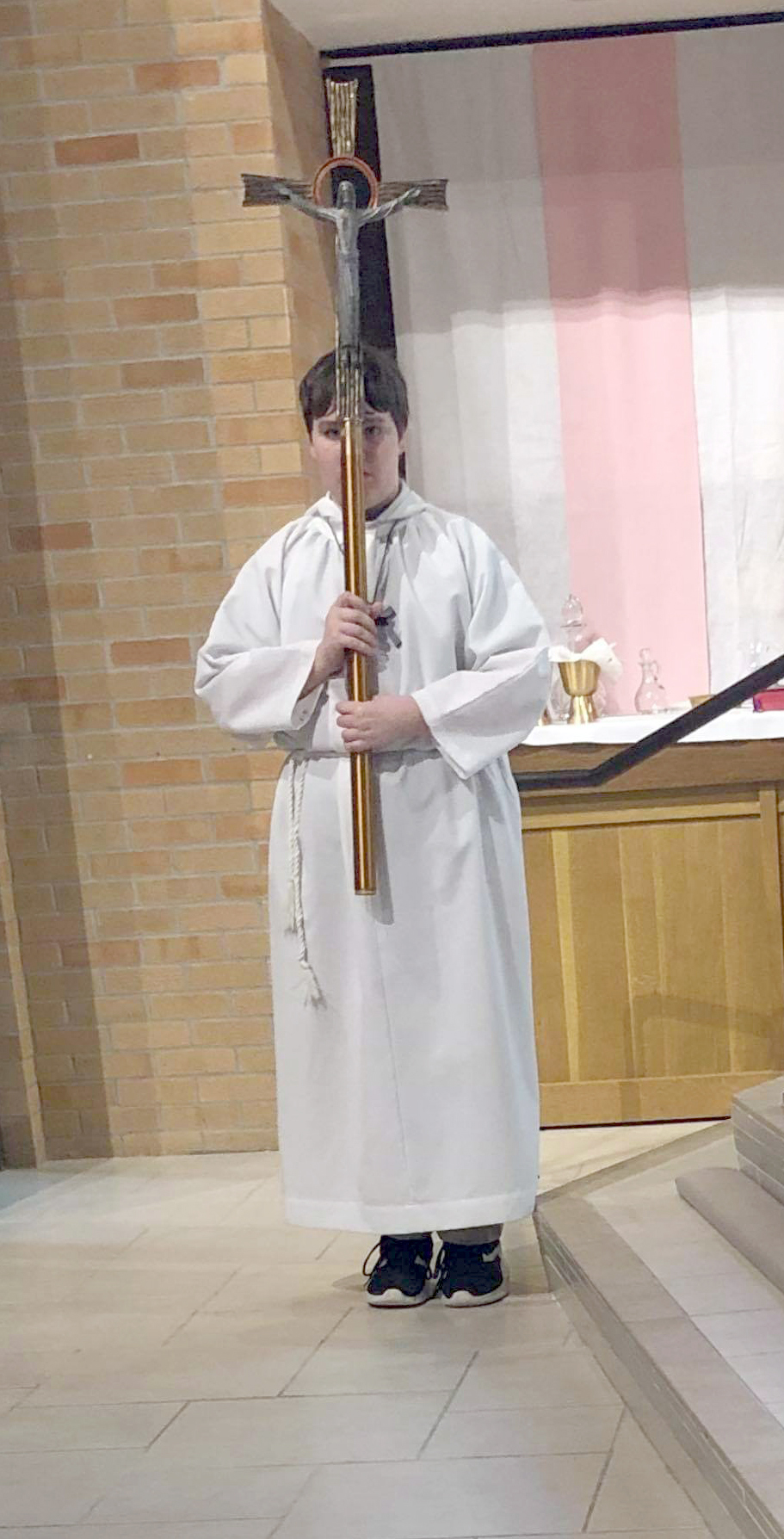 boy alter server carrying crucifix for processional