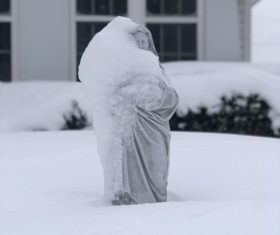 a statue of mother mary covered in snow