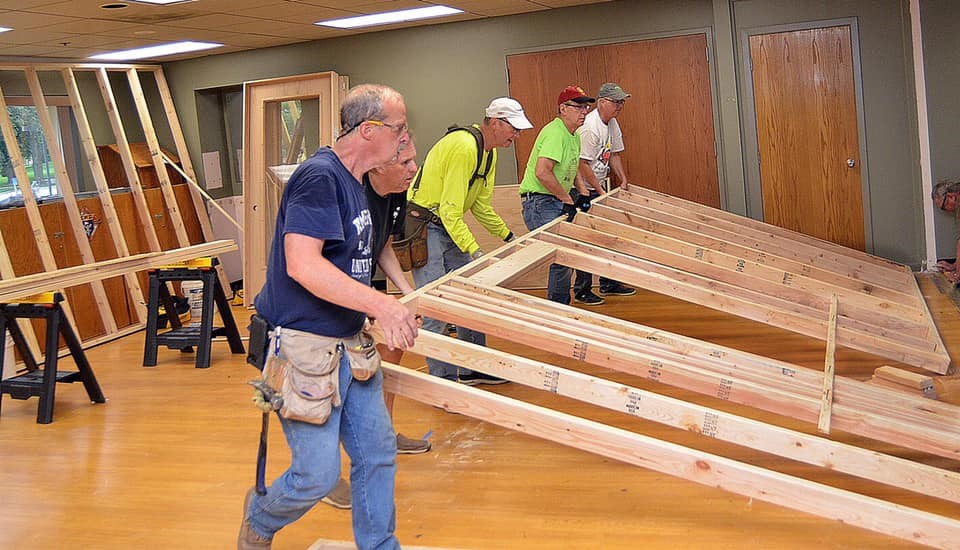 Men help lift a wall under construction