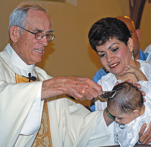 Father Paul Koch baptizes a baby