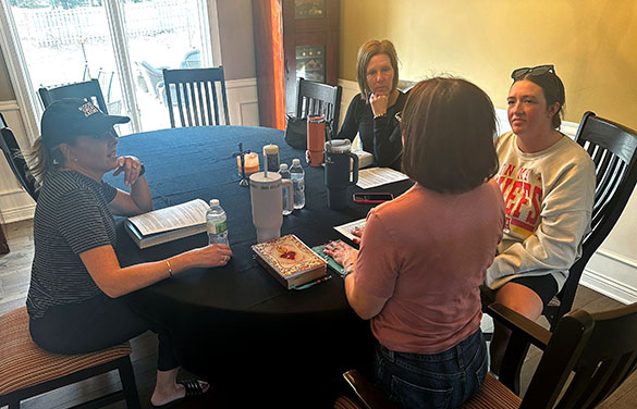 Women talk about faith while sitting at a table