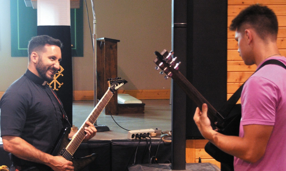 Father Max Carson playing guitar