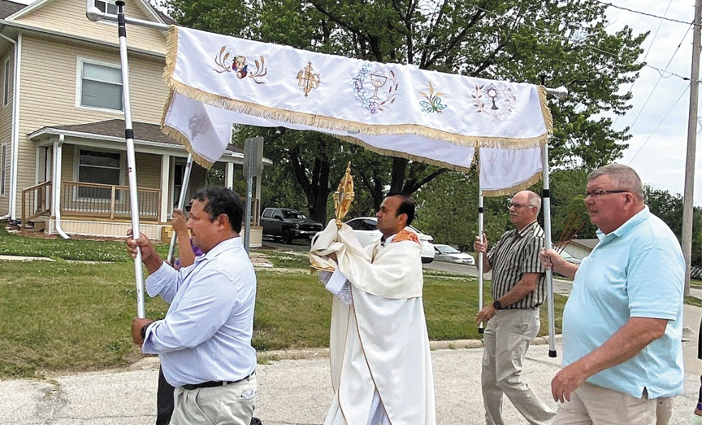 Father Thomson Thomas processes through Osceola in celebration of the Feast of Corpus Christi. Father Thomson Thomas processes through Osceola in celebration of the Feast of Corpus Christi.