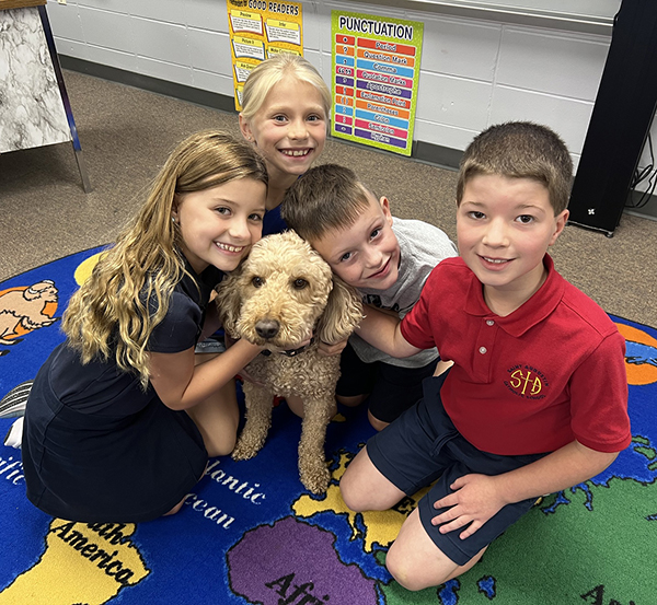 Students gather with Flynn the dog at Saint Augustin Sc