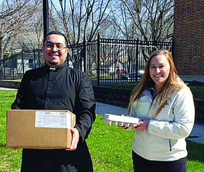 Father Luis Mejia and Kandice Roethler offer food to ne